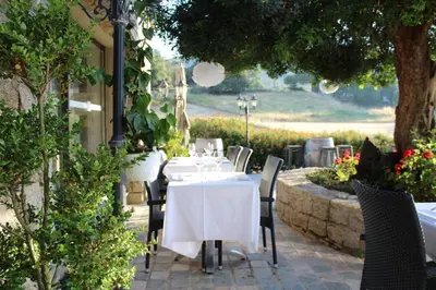 a table with white tables and chairs in a garden at Hôtel & Résidence Les Bergeries d'Alata in Alata