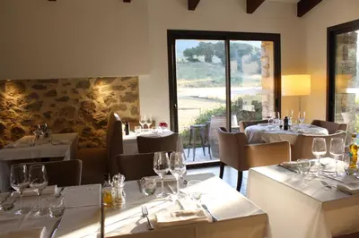 a restaurant with white tables and chairs and a window at Hôtel & Résidence Les Bergeries d'Alata in Alata