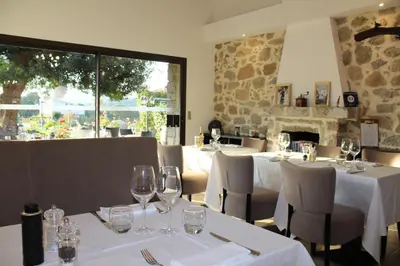 a restaurant with white tables and chairs with wine glasses at Hôtel & Résidence Les Bergeries d'Alata in Alata
