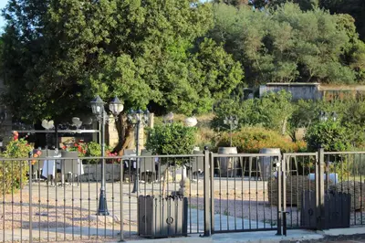 a metal fence with a cemetery behind it at Hôtel & Résidence Les Bergeries d'Alata in Alata