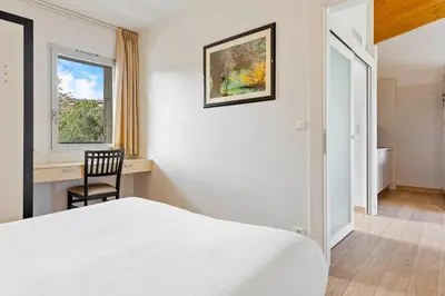 a bedroom with a bed and a chair and a window at Résidence Cala Sultana Appartement T2 in Porto-Vecchio