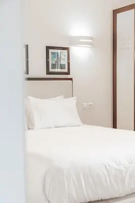 a white bed with white sheets and a mirror at Résidence Cala Sultana Appartement T2 in Porto-Vecchio