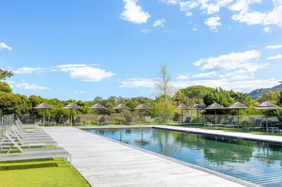 a swimming pool with chairs and umbrellas in a resort at Résidence Cala Sultana Appartement T2 in Porto-Vecchio