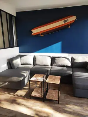 a living room with a couch with a surfboard on the wall at Superbe T1 neuf avec vue mer sur Marinella in Ajaccio