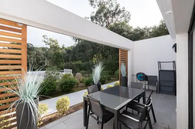 a dining room with a table and chairs on a patio at L'Ebene in Coti-Chiavari