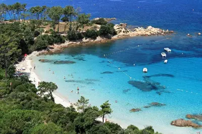 a beach with people swimming in the blue water at L'Ebene in Coti-Chiavari