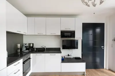 a kitchen with white cabinets and a black refrigerator at L'Ebene in Coti-Chiavari