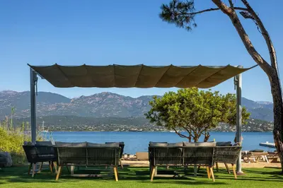 a group of chairs and a gazebo with a view of the water at Hotel Restaurant Mariosa in Porto-Vecchio
