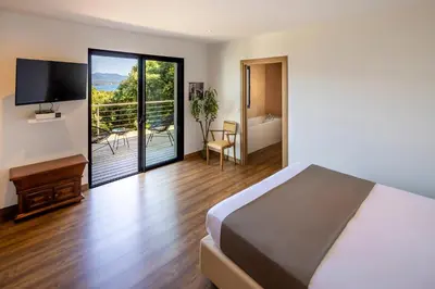 a bedroom with a bed and a balcony with a television at Hotel Restaurant Mariosa in Porto-Vecchio