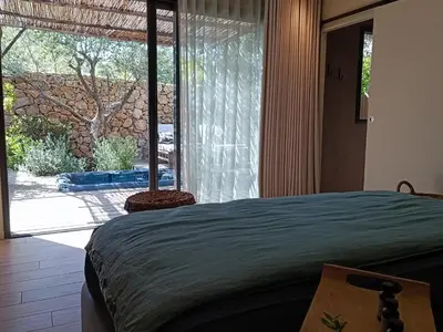 a bedroom with a bed and a large window at Hôtel Les Suites Du Maquis in Bonifacio