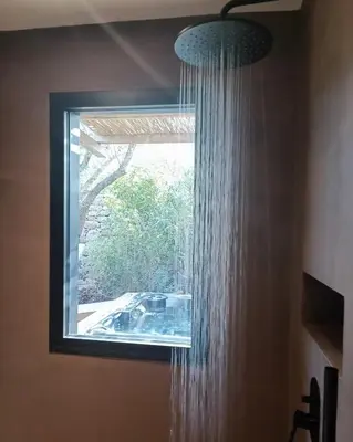 a shower in a bathroom with a window at Hôtel Les Suites Du Maquis in Bonifacio