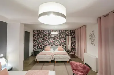 a bedroom with two beds and a floral wallpaper at Hôtel Spunta Di Mare in Ajaccio