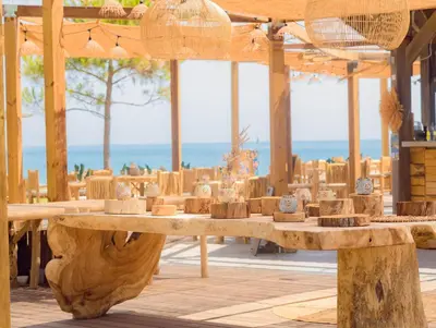 a large wooden table with benches in front of the ocean at Hôtel San Lucianu in Moriani Plage