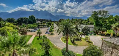 an aerial view of a park with palm trees and mountains at Hôtel San Lucianu in Moriani Plage