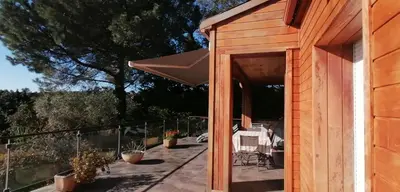 a wooden house with a patio with chairs and an umbrella at VILLA ANGELINI in Valle-di-Campoloro