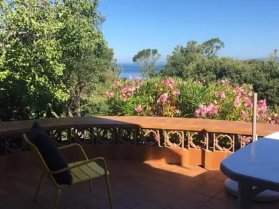 a patio with a table and chairs and flowers at Villa PLEIN SOLEIL- Plage d'Argent à 150 m - 150 m from beach in Coti-Chiavari