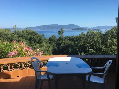 a table and chairs on a balcony with a view of the water at Villa PLEIN SOLEIL- Plage d'Argent à 150 m - 150 m from beach in Coti-Chiavari