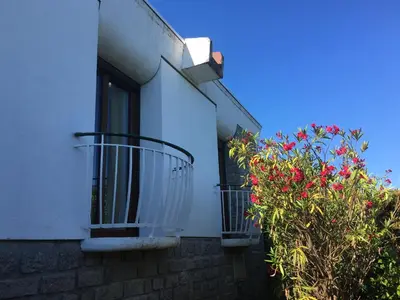 a white building with two balconies and red flowers at Villa PLEIN SOLEIL- Plage d'Argent à 150 m - 150 m from beach in Coti-Chiavari