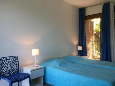 a bedroom with a bed and a chair and a window at Villa PLEIN SOLEIL- Plage d'Argent à 150 m - 150 m from beach in Coti-Chiavari
