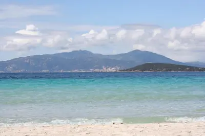 a beach with the ocean and mountains in the background at Villa PLEIN SOLEIL- Plage d'Argent à 150 m - 150 m from beach in Coti-Chiavari