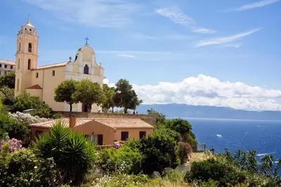 a church on a hill next to the ocean at Résidence Castugna in Cargèse