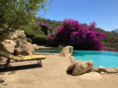 a bench sitting next to a swimming pool with rocks at Villas Valinco San Martinu Corse du Sud - vue et proche mer - piscines-7 chambres in Olmeto