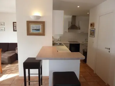 a kitchen with a table and two stools at Villas Valinco Capicciolo vue-proche mer-piscines in Olmeto