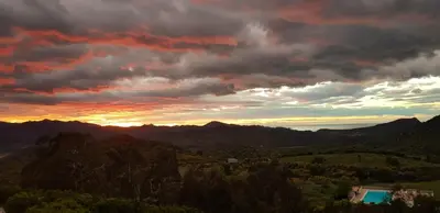 a sunset over a mountain range with a pool at Hôtel 