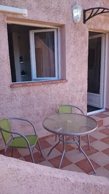 a patio with a table and two chairs and a window at Hôtel 