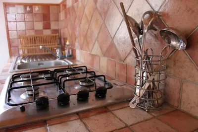 a kitchen counter with a stove and a sink at A MANDRIA, appartements avec cuisine 30m2, patio, vue Montagnes et citadelle, 5 minutes à pied du centre ville et des rivières in Corte