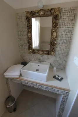 a bathroom with a sink and a mirror on a wall at A MANDRIA, appartements avec cuisine 30m2, patio, vue Montagnes et citadelle, 5 minutes à pied du centre ville et des rivières in Corte