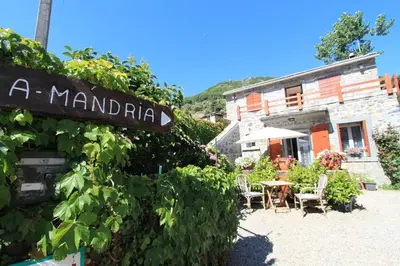 a sign in front of a building with a table and chairs at A MANDRIA, appartements avec cuisine 30m2, patio, vue Montagnes et citadelle, 5 minutes à pied du centre ville et des rivières in Corte