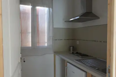 a kitchen with a sink and a stove and a window at A MANDRIA, appartements avec cuisine 30m2, patio, vue Montagnes et citadelle, 5 minutes à pied du centre ville et des rivières in Corte