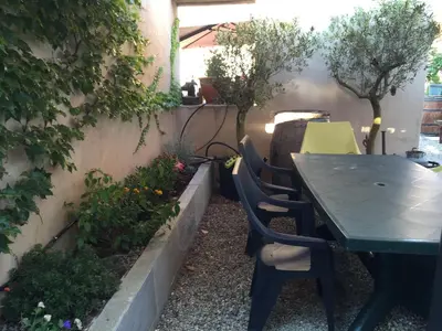 a table and chairs in a garden with plants at A MANDRIA, appartements avec cuisine 30m2, patio, vue Montagnes et citadelle, 5 minutes à pied du centre ville et des rivières in Corte
