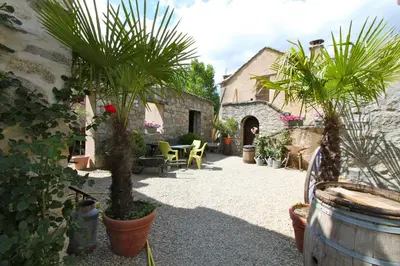 a courtyard with palm trees and a building at A MANDRIA, appartements avec cuisine 30m2, patio, vue Montagnes et citadelle, 5 minutes à pied du centre ville et des rivières in Corte