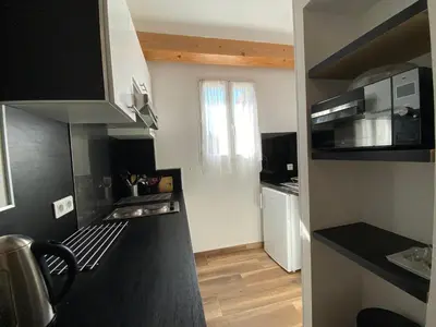 a small kitchen with a black counter top at A MANDRIA, appartements avec cuisine 30m2, patio, vue Montagnes et citadelle, 5 minutes à pied du centre ville et des rivières in Corte