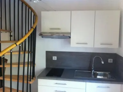 a kitchen with a sink and white cabinets and a staircase at Peri village in Peri