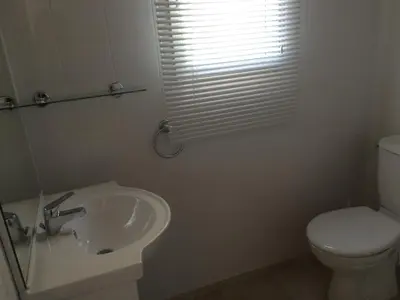 a white bathroom with a toilet and a sink at Peri village in Peri