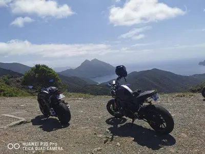 two motorcycles parked on a hill with mountains in the background at Villa Solsticia in Porticcio