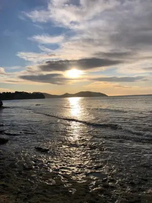 a sunset on a beach with the sun reflecting on the water at Villa Solsticia in Porticcio