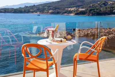 a table and chairs with a view of the water at Hotel le Jardin d'Emile in Porticcio