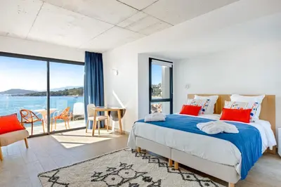a bedroom with a bed and a view of the water at Hotel le Jardin d'Emile in Porticcio