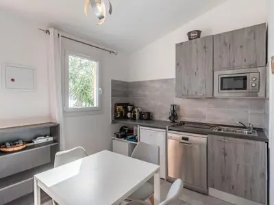 a kitchen with a white table and a white table and chairs at Holiday Home Mustella by Interhome in Sari Solenzara