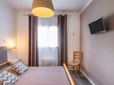 a bedroom with a bed and a chair and a television at Holiday Home Scorpina by Interhome in Sari Solenzara