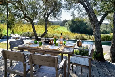 a wooden table and chairs on a wooden deck at Domaine de Peretti della Rocca in Figari