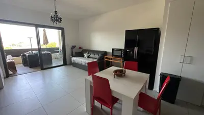 a kitchen and living room with a table and red chairs at Studio T1 bis vue mer Propriano in Propriano