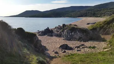 a beach with rocks and water and mountains at Studio T1 bis vue mer Propriano in Propriano