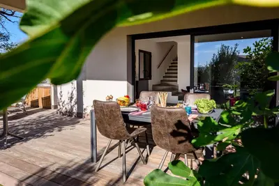 a patio with a table and chairs on a deck at Calarossa Bay Resort in Porto-Vecchio