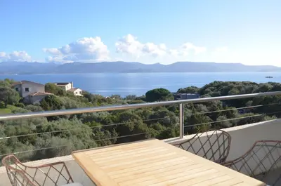 a balcony with a table and chairs and a view of the water at Résidence Giovanello in Porto Pollo