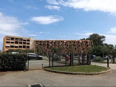 a building with a fence in front of a building at Residence Santa Lucia, studio avec piscine , vue mer et pied dans l'eau , Moriani-Plage in Santa-Lucia-di-Moriani